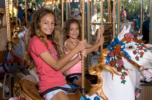 Image of two little girls smiling on carousel horses