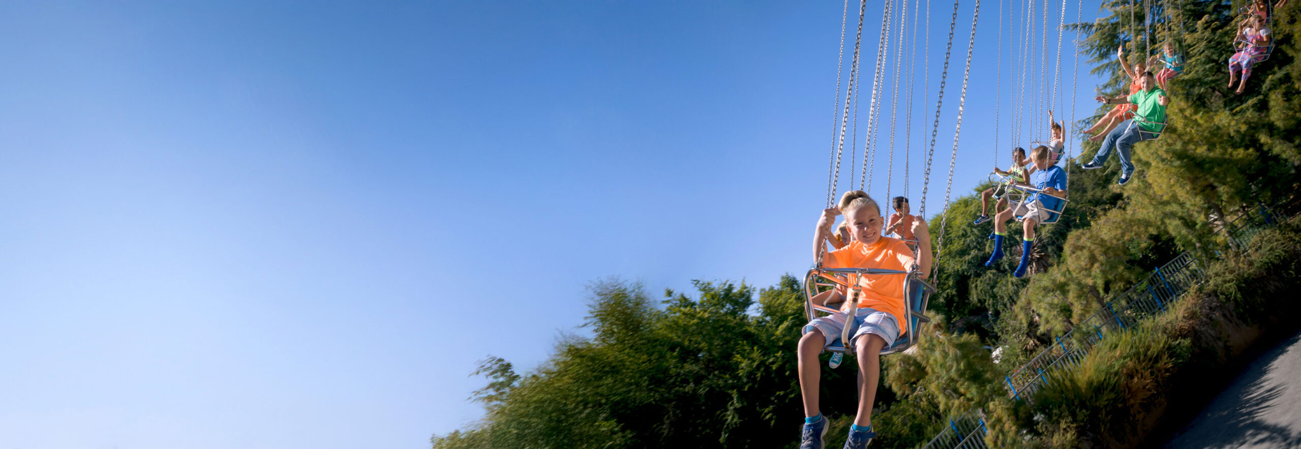 Children in colorful clothes smiling while on the Mushroom Swing