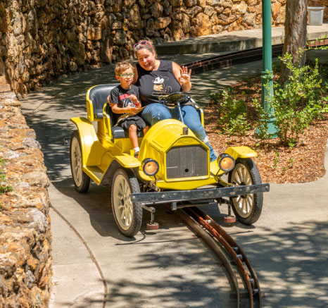 Mother in black tank top waving with her son in black shirt while on a yellow car on the South County Backroads ride