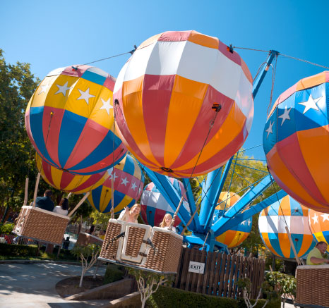 Families riding and waving on the Balloon Flight ride on a sunny day