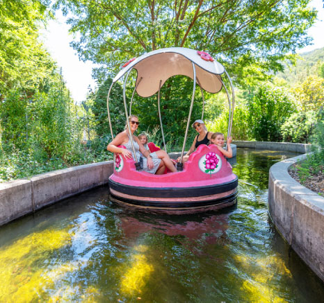 Two women in sunglasses and two girls smiling on the Rainbow Garden Round Boats ride