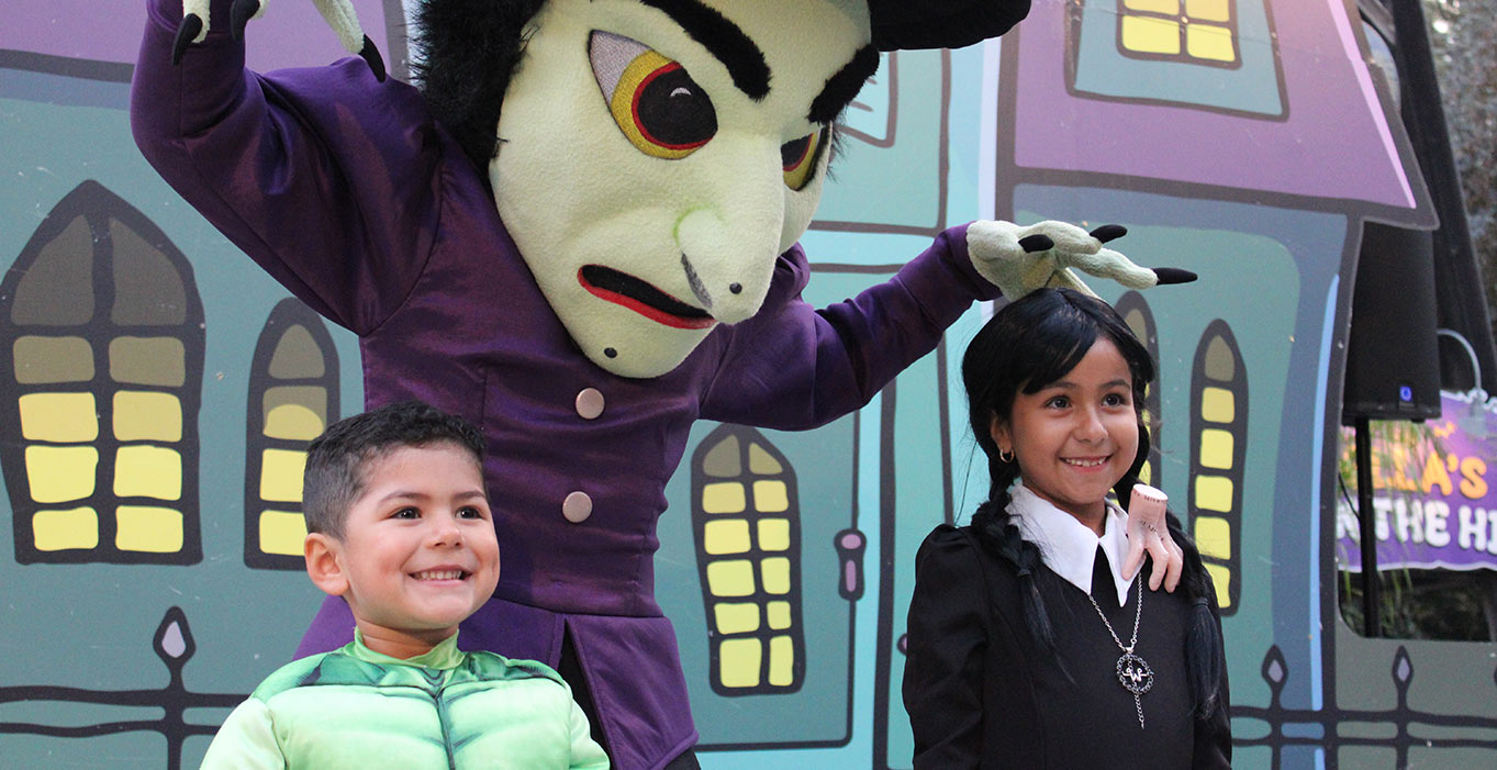 Young boy dressed as Hulk and young girl dressed as Wednesday taking a picture with Windella the Witch at the Great Big BOO Event