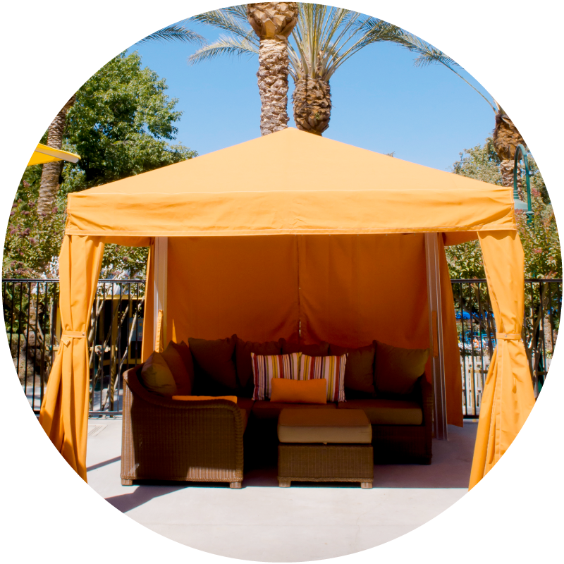 Light orange cabana with brown lounge chairs and red, white, yellow stripped pillow