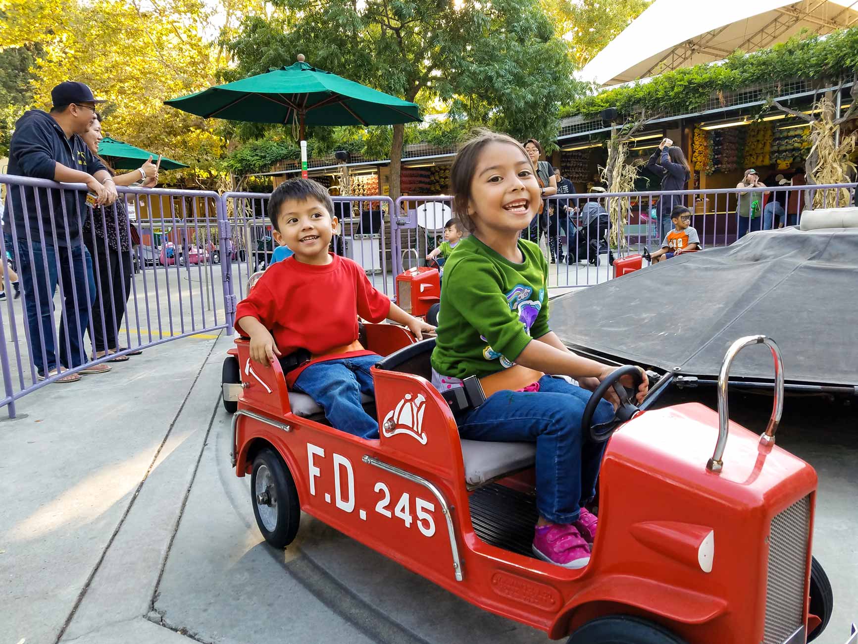 Young girl in green sweatshirt and boy in red shirt smiling on the Big Red Engine Co ride