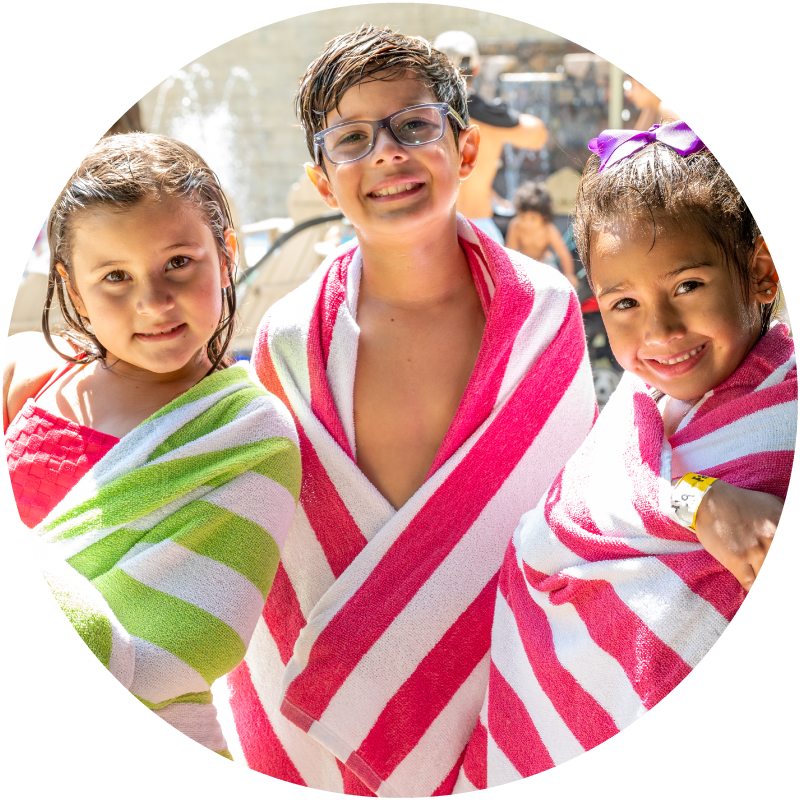 Children smiling while wrapped in green, pink, and white striped towels at Water Oasis