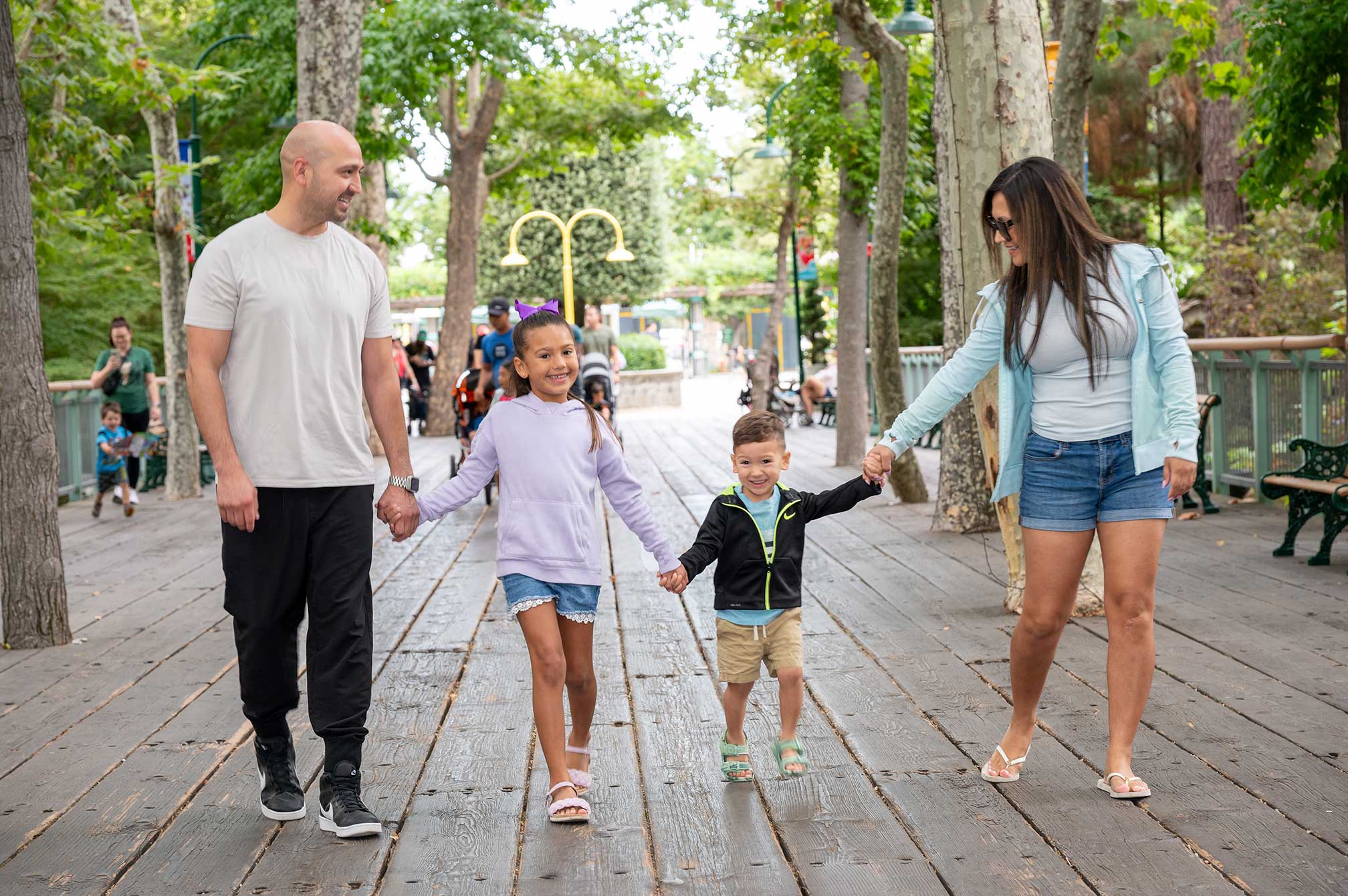 Happy family of four holding hands while walking on Sycamore Bridge