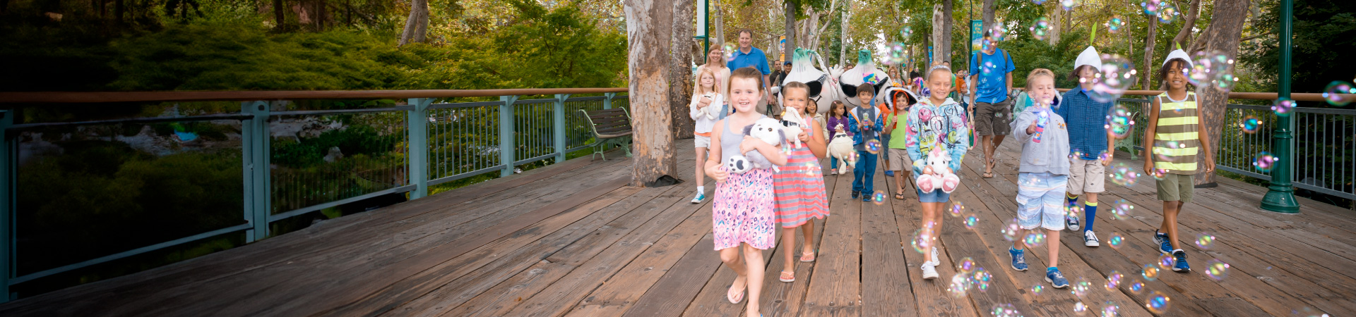 A group of young children walking across the Sycamore Bridge while blowing bubbles