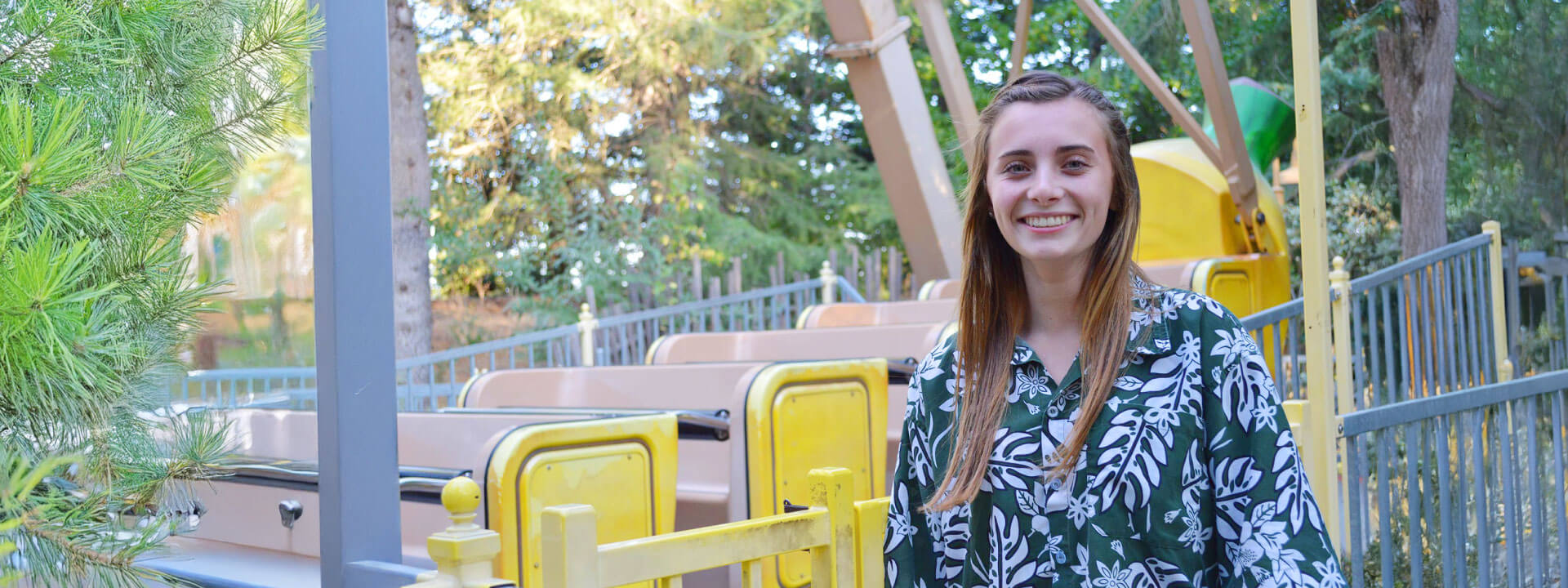 Girl with blonde hair smiling in front of the Banana Split ride.