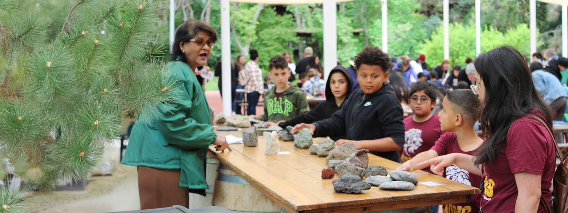 Children in red and black shirts learning about rocks