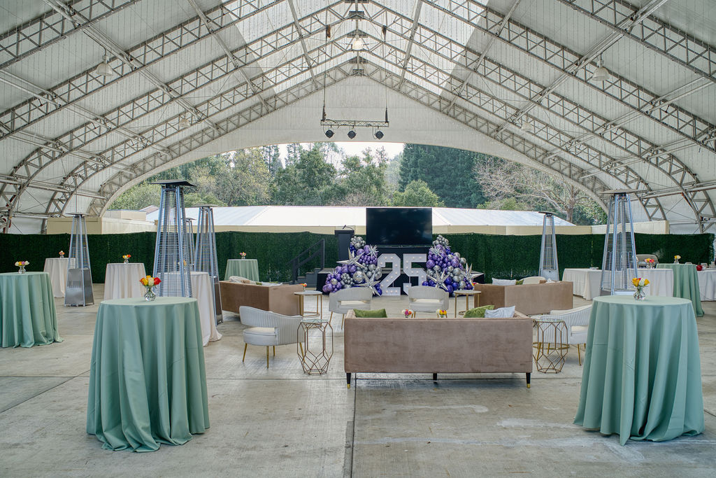 Tall circular tables with light green and white table covers with heat laps near by and tan couches for extra seating