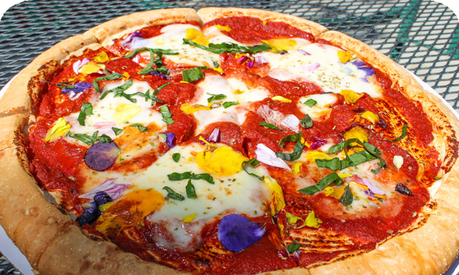 Cheese pizza with edible yellow, purple, and green flowers
