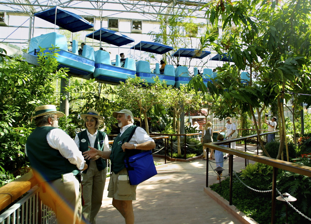 Sky Trail Monorail passing over the Monarch Garden while people walk through the garden and take photos