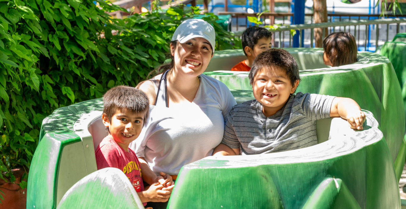 Mother wearing a white hat sitting with two sons smiling inside of the Artichoke Dip ride