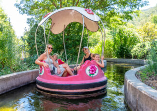 Two women in sunglasses and two girls smiling on the Rainbow Garden Round Boats ride
