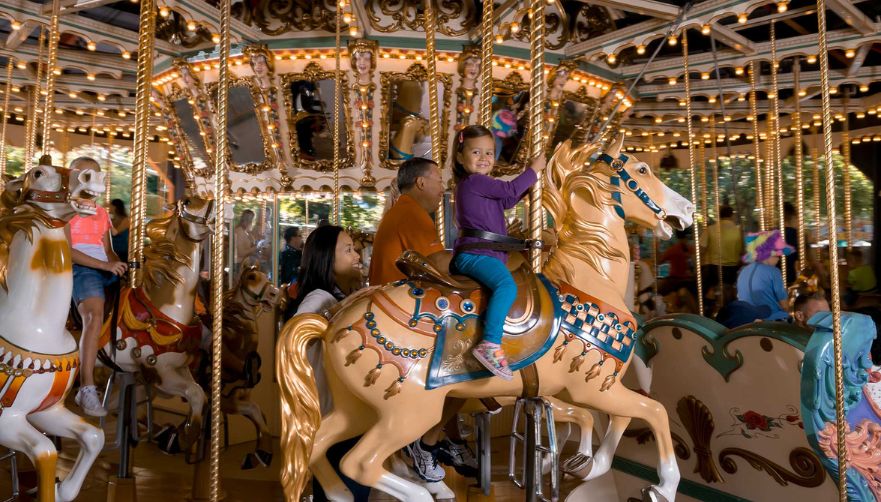 Little girl in a purple long sleeve shirt and blue pants smiling while on the Illinois Supreme Carousel