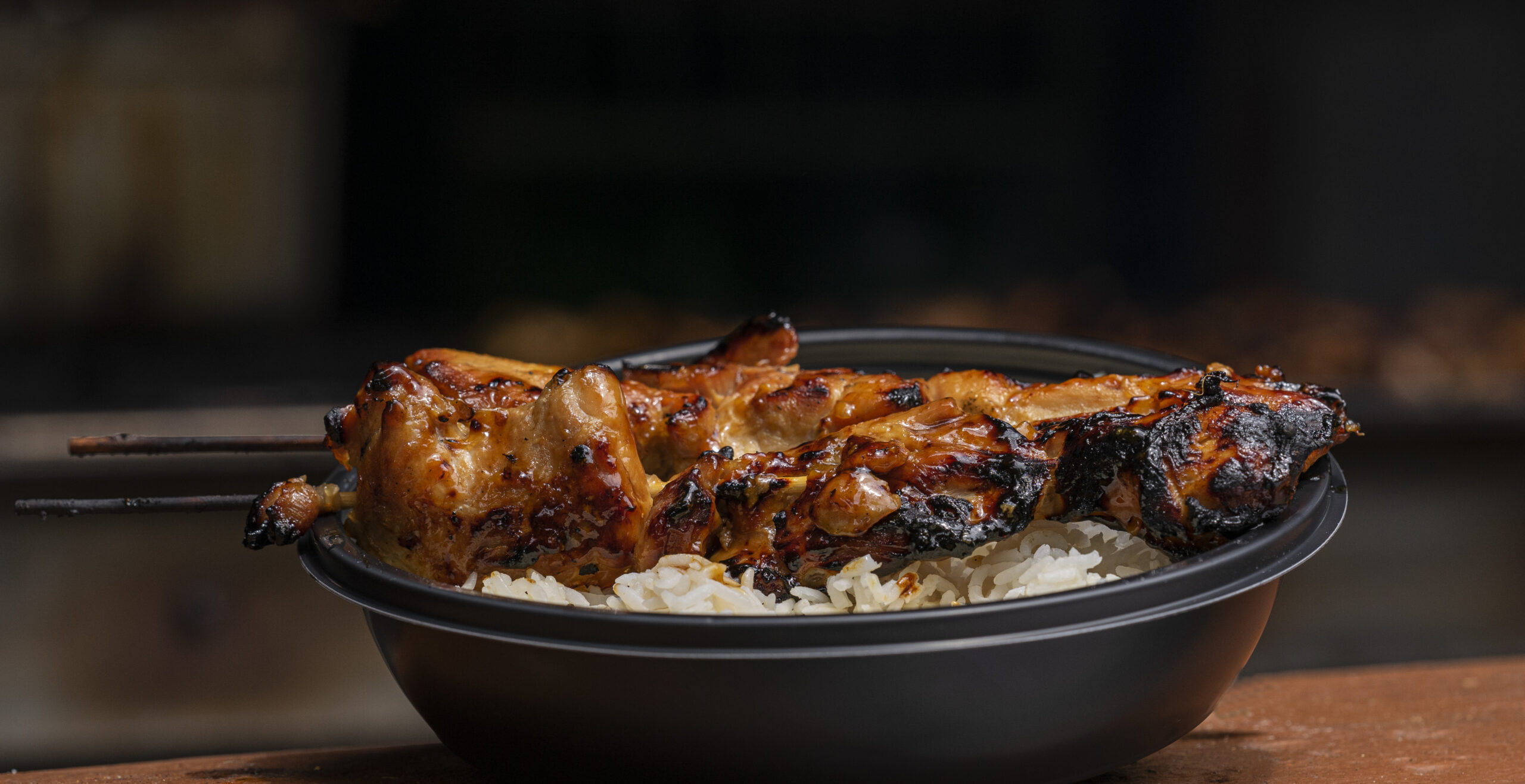 Black bowl with white rice and teriyaki chicken