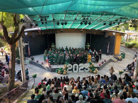 Class of 2025 on stage in green graduation gowns