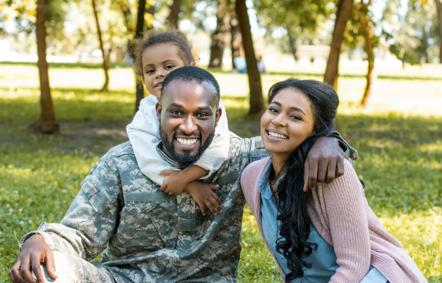Man in Army outfit smiling with his wife and daughter
