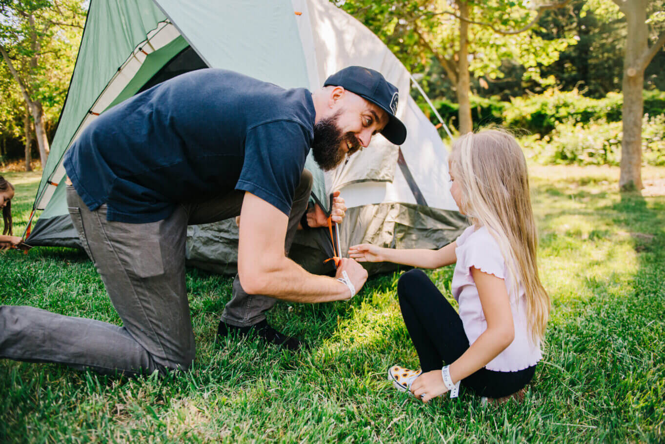 A dad putting a tent together with the help of his daughter