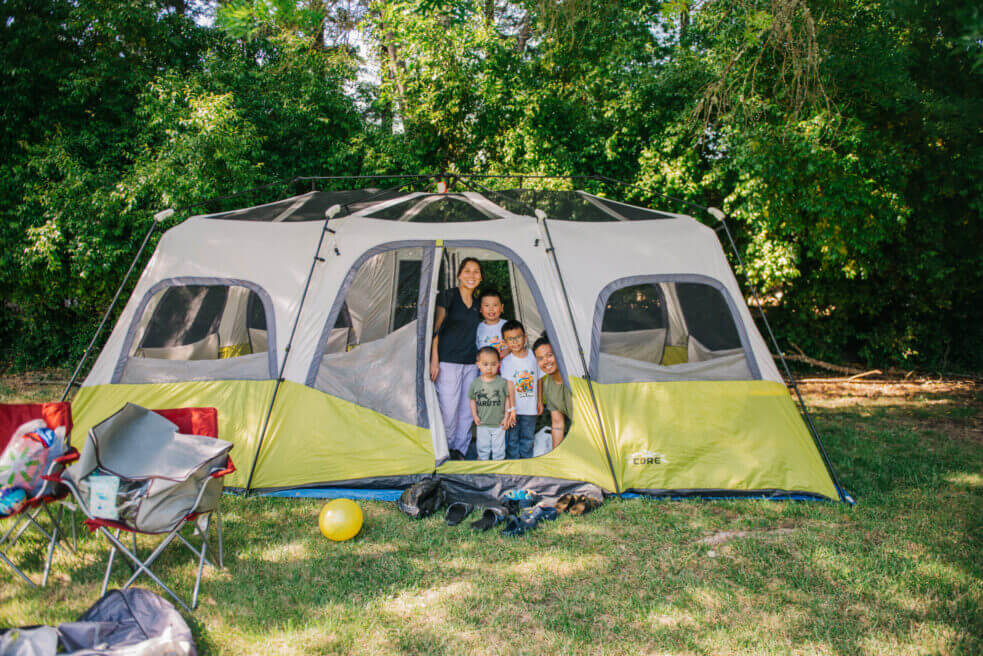 Family smiling while inside of their large tan and light green tent