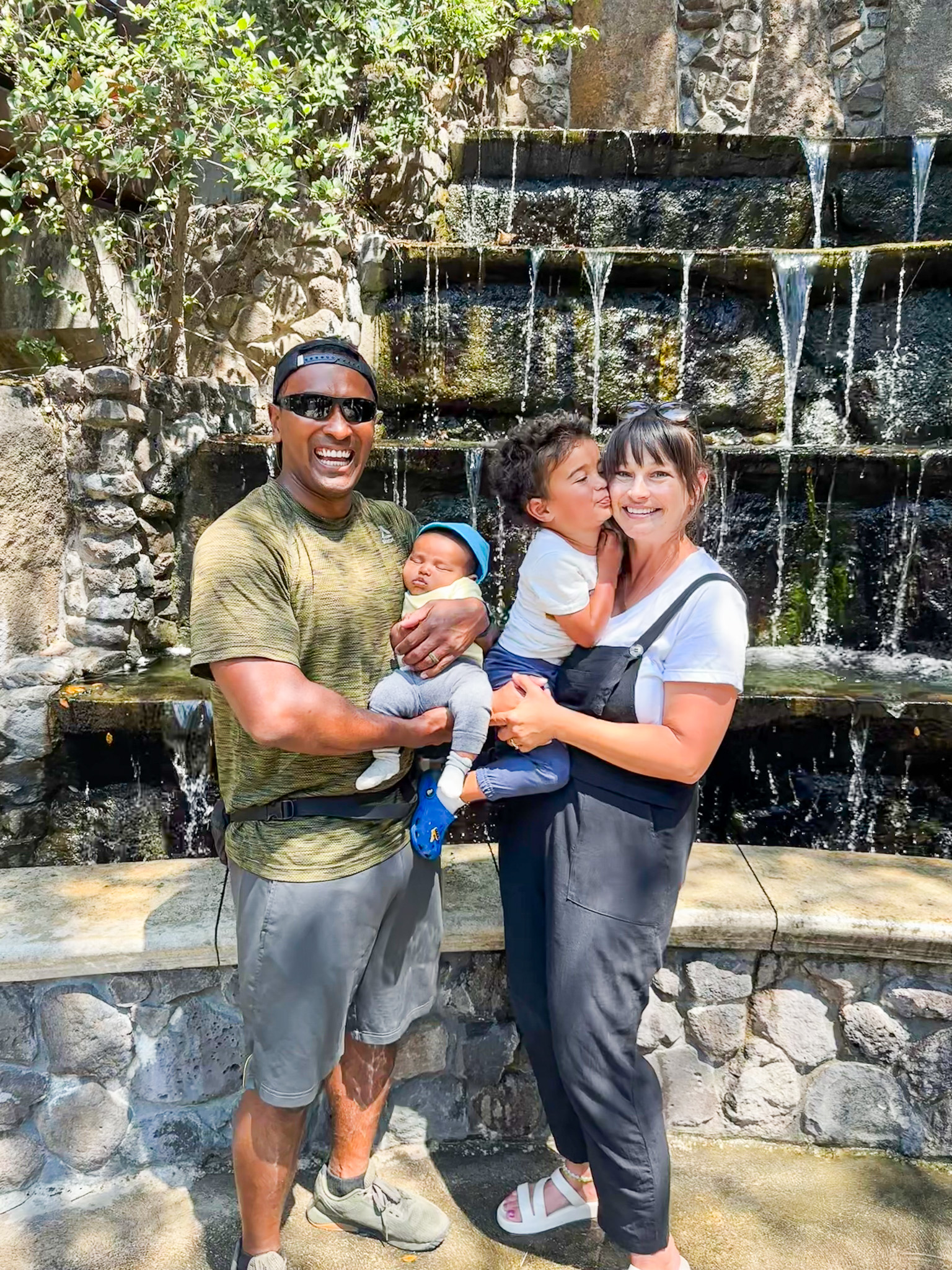 Family of four standing in front of a water fountain located at Bonfante Falls.