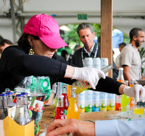 Bartender in a hot pink hat pouring soda into a cup