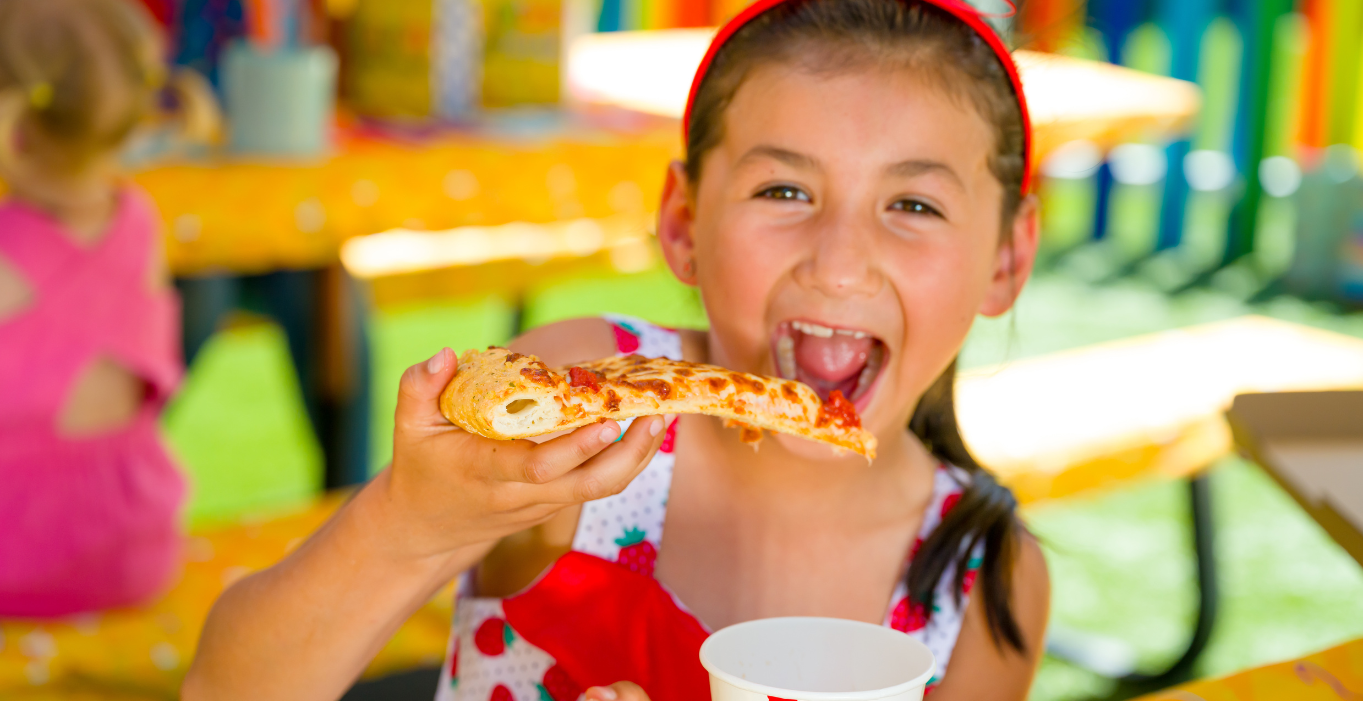 Young girl in a strawberry dress eating cheese pizza