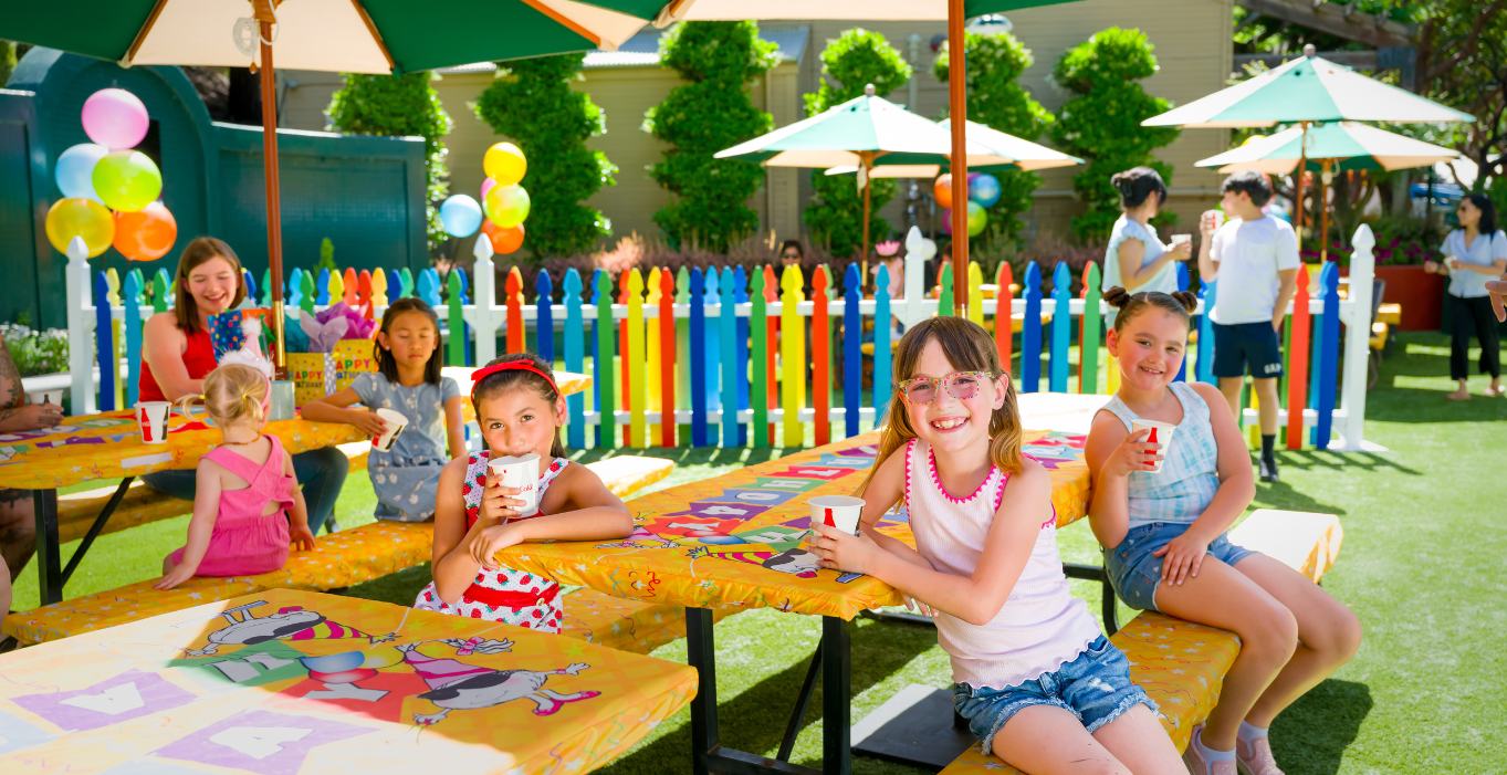 Children holding cups and drinking juice and smiling at a birthday party