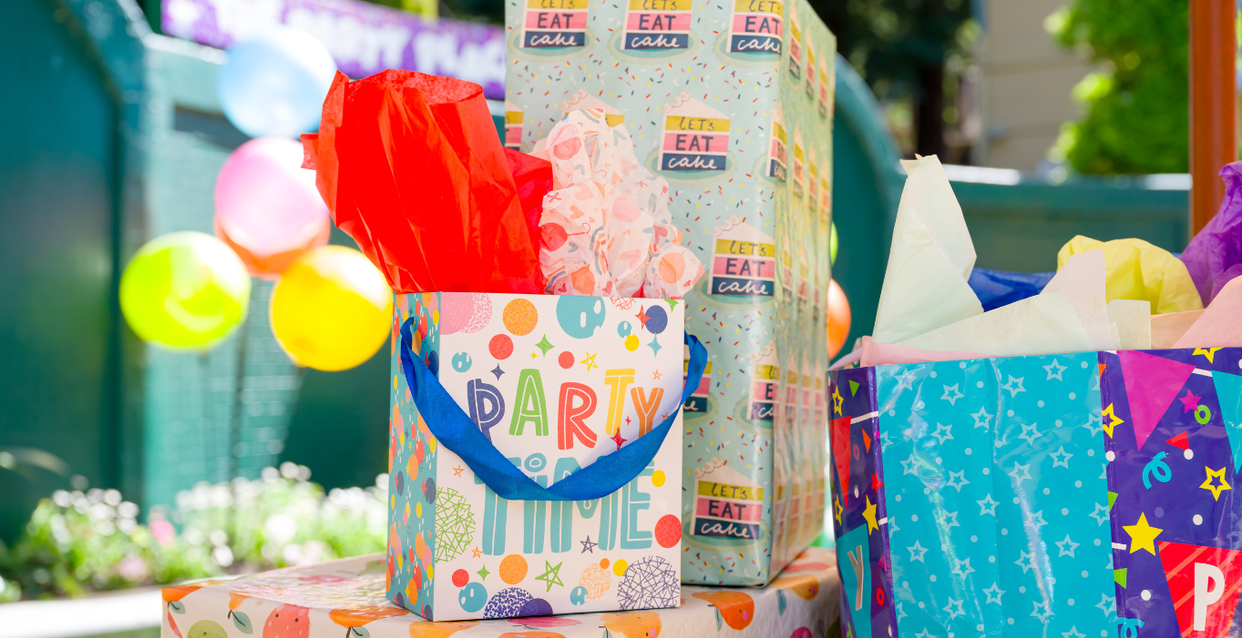 Multiple birthday bags and presents on a table