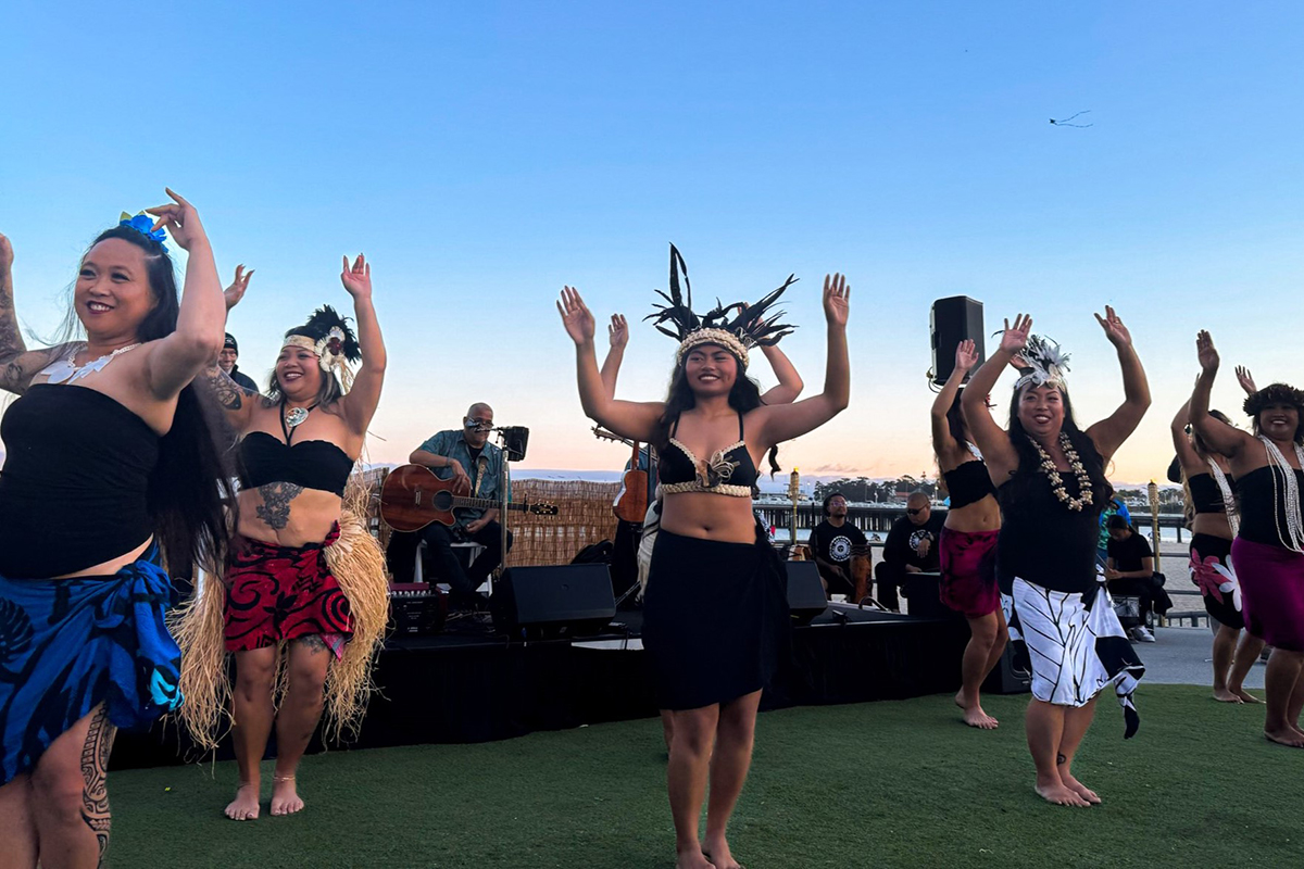 Group of women smiling while performing in a luau
